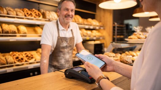 Kundin bezahlt in der Bäckerei per Smartphone-Wallet am Kartenterminal