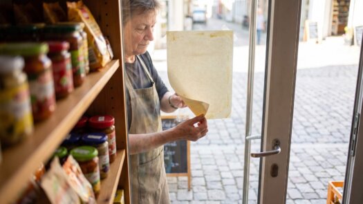 Ladeninhaberin löst ein altes Papierschild von ihrer Eingangstür
