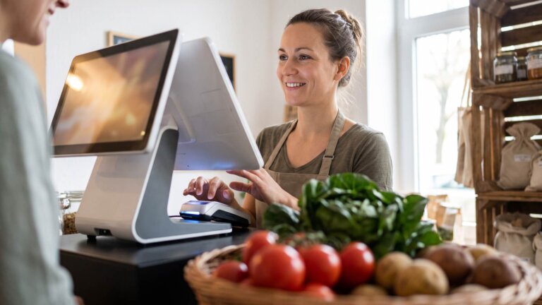 Kassiererin bedient ein Kassensystem mit integriertem Kartenterminal im Hofladen
