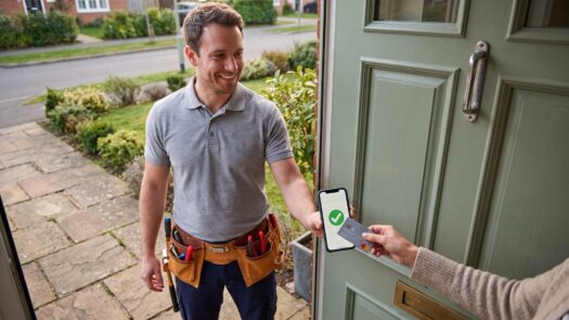 Handwerker nimmt an der Haustür eine Kartenzahlung per Smartphone entgegen