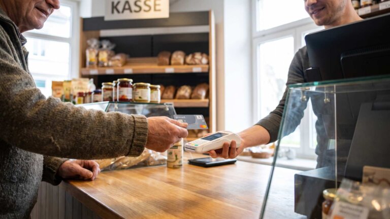 Kunde hält seine girocard an das Terminal des Verkäufers